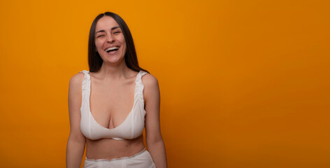 Obraz premium Laughing makeup-free woman on orange background with copy space