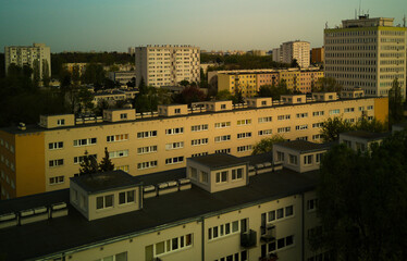 Aerial view of geometric roofs and multi-story residential buildings in eastern european city during golden hour © Mateusz