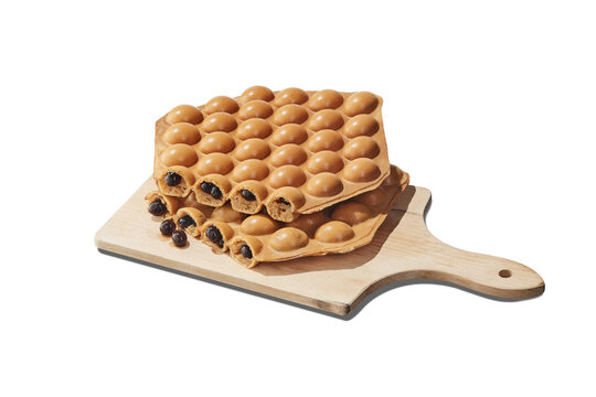 Famous Hong Kong style egg waffle bubble waffle filled with tapioca boba pearls on a wooden cutting board, isolated.