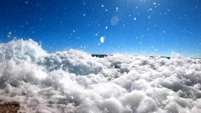 Stunning ocean wave breaking in slow motion under a bright sunny sky with clear blue water and sea foam