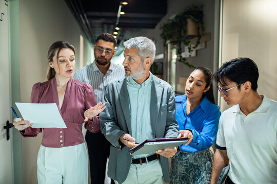 Business team discussing project in office hallway