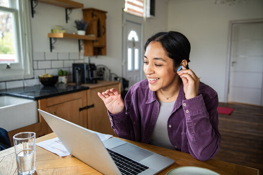 Young woman on video call at home kitchen table