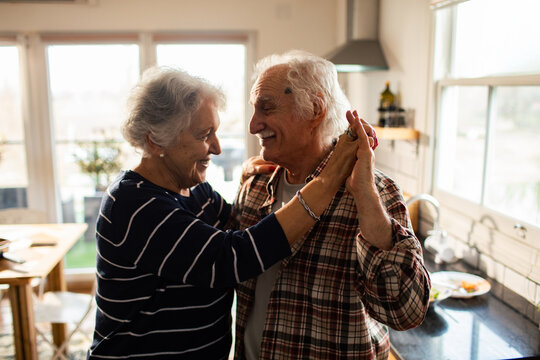 Smiling senior couple dancing in home kitchen