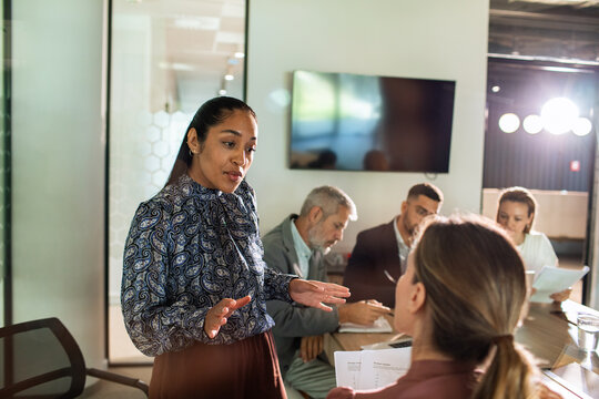 Businesswoman presenting to colleagues in modern office conference room