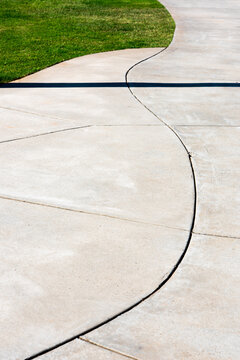 Curving white concrete path through green grass