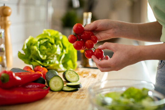 Person preparing fresh vegetable salad in a home kitchen