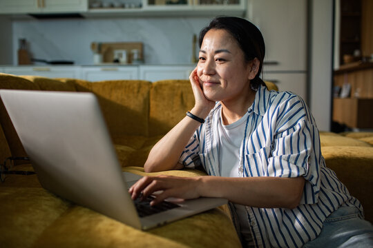 Smiling woman using laptop on sofa at home