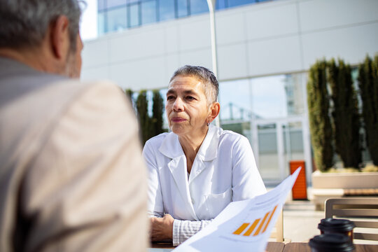 Senior female doctor consulting patient outside hospital