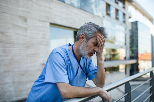 Stressed healthcare worker in scrubs outside hospital