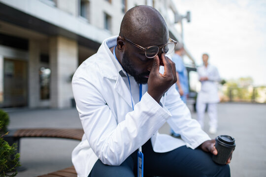 Stressed doctor with coffee resting outside hospital