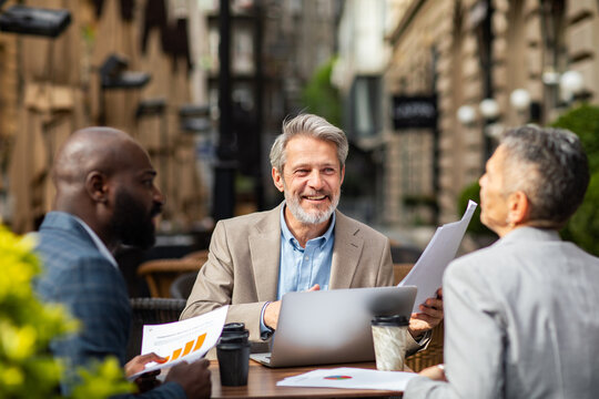 Business colleagues meeting with laptop at outdoor cafe