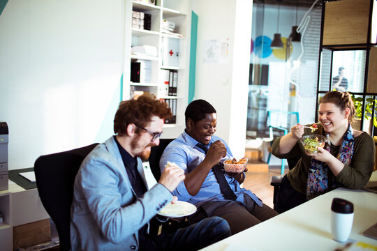 Diverse coworkers eating lunch together in office