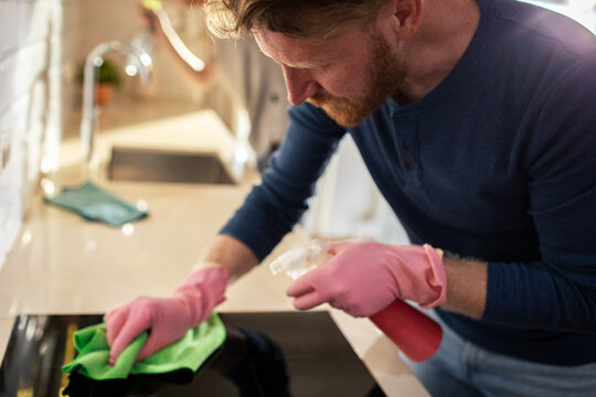 Man cleaning home kitchen stovetop with spray