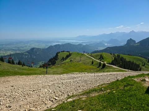 Germany, Chair Lift Side Panorama With Forgensee Lake Alpine Peaks And Scenic Trail Across Breitenberg Heights
