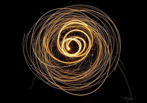 Golden light painting with sparks and trails, isolated on transparent background, showcasing a dynamic spiral pattern from slow shutter speed photography.