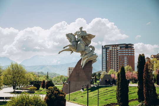 Equestrian monument in Vladikavkaz with Caucasus Mountains and dramatic clouds in the background on a sunny spring day