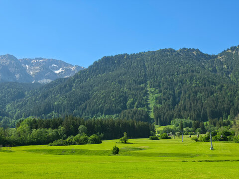 Germany, Stunning Alpine Valley Panorama Rising Through Emerald Pastures Toward Breitenberg Cable Car Line Beneath Brilliant Summer Sky