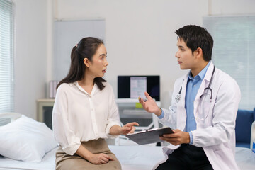 Fototapeta premium Young Asian doctor providing medical consultation to a female patient, discussing diagnosis and treatment options in a hospital clinic