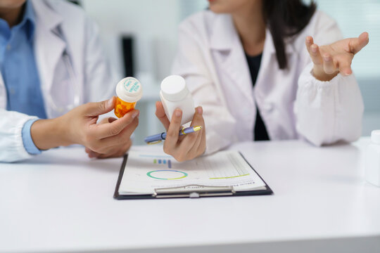 Healthcare workers comparing medicine bottles, discussing pharmaceutical treatment plans and patient health data in a clinical environment