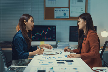 Fototapeta premium Business women discussing financial data, analyzing stock market trends, and planning corporate strategy in a modern office