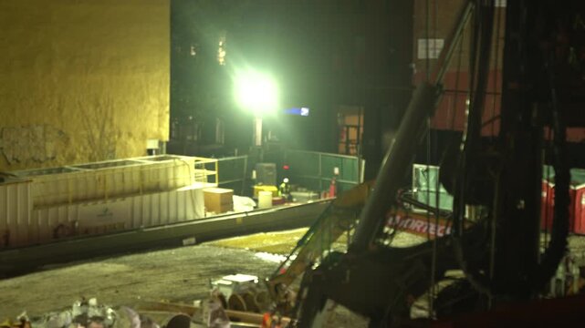 A cinematic nighttime video clip of an industrial drilling machine at a construction site.
