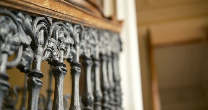 cinematic video featuring a magnificent cast-iron staircase inside a historic mansion, captured while slowly ascending upward through the elegant interior. The staircase showcases intricate ornamental