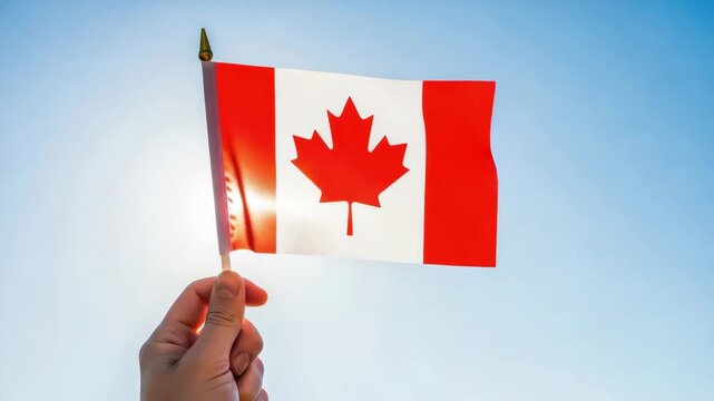Hand holding a small canadian flag waving in the wind outdoors