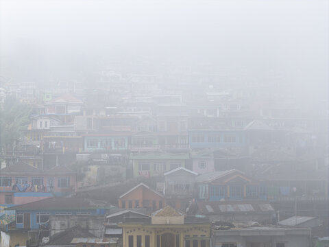 Aerial view of Nepal Van Java village with colorful houses nestled on a hillside shrouded in thick morning fog and mist in Kecamatan Kaliangkrik, Jawa Tengah, Indonesia.