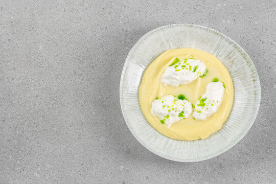 Creamy mashed potatoes with stracciatella cheese served on plate over gray background