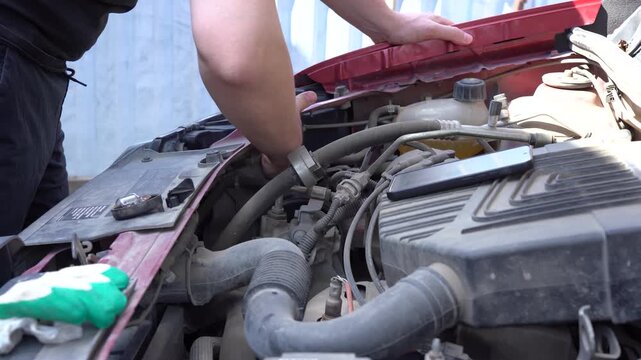 A Mechanic Diagnosing Engine Issues Under the Hood: Close-Up of Hands Working on an Automotive Repair Project with Tools in a Vehicle's Engine Compartment