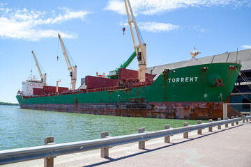 Naklejka premium Toronto, Ontario, Canada - June 19, 2018: The bulk carrier ship Torrent docked at the Redpath Sugar Refinery in Toronto, Ontario, Canada. The Redpath Sugar Refinery is a sugar storage, refining and mu