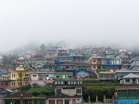 Aerial view of the colorful houses of Nepal Van Java village nestled on a misty mountain slope in Kecamatan Kaliangkrik, Jawa Tengah, Indonesia.