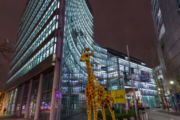 Naklejka premium Huge plastic giraffe statue in front of the Legoland Discovery center, night shot in Berlin, Germany