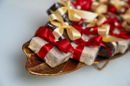 traditional brazilian bem casado wedding sweets on golden platter, wrapped party favors with red and gold ribbons, high angle view of artisanal confectionery desserts with copy space