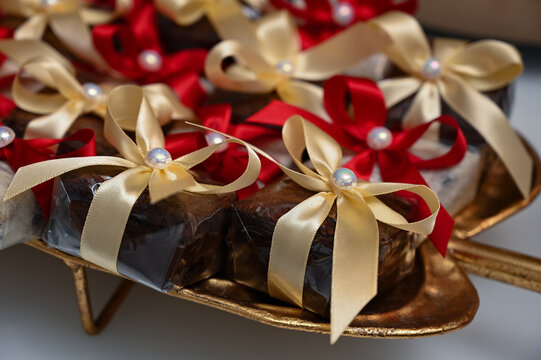 traditional brazilian bem casado wedding sweets on golden platter, wrapped party favors with red and gold ribbons, high angle view of artisanal confectionery desserts with copy space