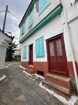 Colorful house located on a narrow street in a small town with blue shutters and red doors during daytime