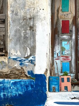 Colorful wall art with sailboat near buildings in a coastal town during daytime