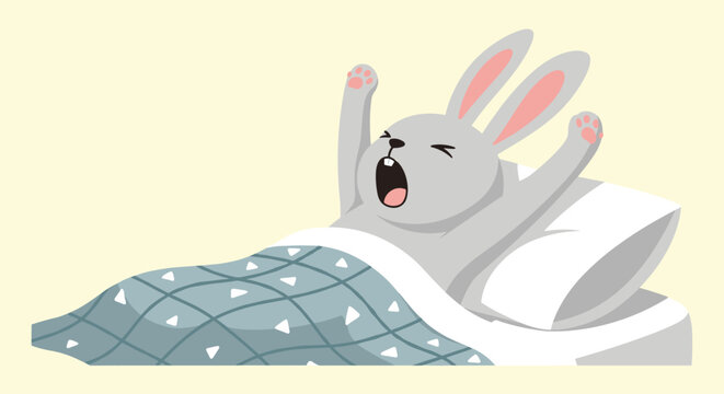 Tired gray rabbit tucked into bed under a blue patterned blanket stretches its arms and yawns widely after waking up.