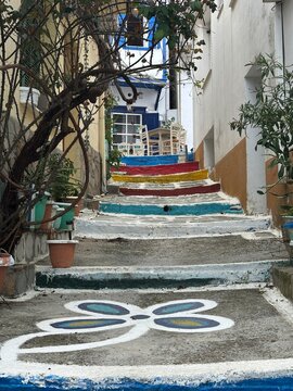 Colorful steps go up a narrow path surrounded by buildings in a small town in Greece during daylight hours