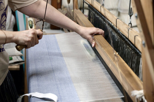 A person weaving fabric on a traditional loom