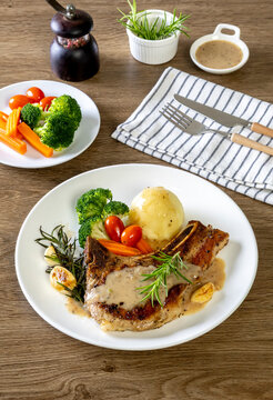  Grilled pork chop steak with baked potatoes, tomatoes and Broccoli, carrot on white plate