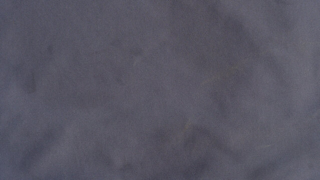Full-frame close up of a soft dark grey microfiber cloth or suede fabric texture. Featuring subtle organic folds smooth pile directions and rich shadow depths.
