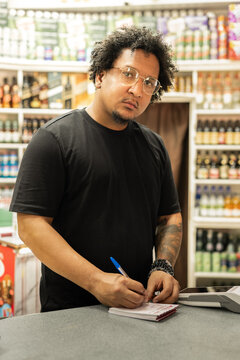 Male cashier working in small shop completing paperwork