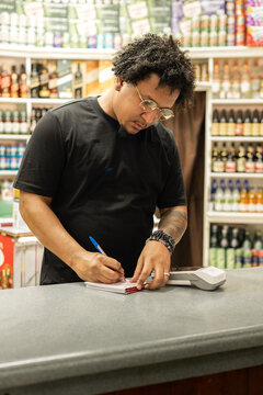 Store worker writing orders at shop counter