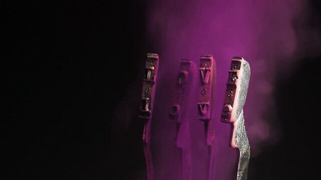 The word love with a vintage typewriter hammers with purple smoke 