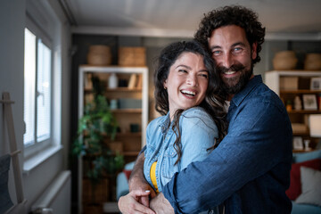 Fototapeta premium Happy couple embracing in living room laughing