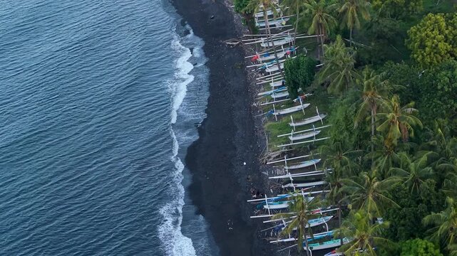 High angle aerial shot of traditional Balinese jukung boats on black sand beach