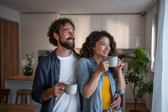 Happy couple enjoying morning coffee in kitchen at home