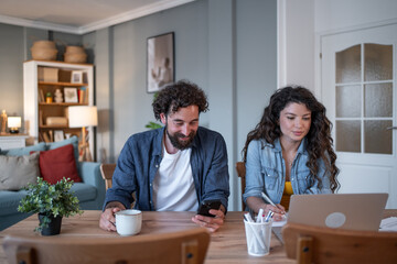 Fototapeta premium Couple working from home using laptop and smartphone