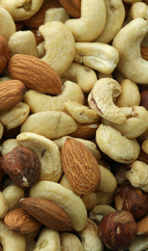 Detailed view on almond and cashew nuts in big pile on table close up